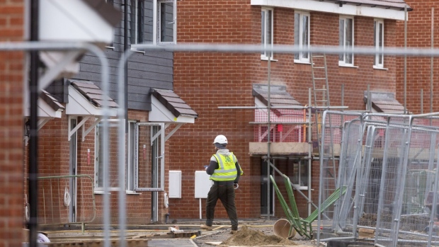 An employee walks through a Taylor Wimpey Plc residential housing construction site in Hoo, UK.