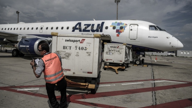 A ground crew member pulls a cart of baggage from an Azul passenger aircraft at Viracopos International Airport in Campinas, Brazil.