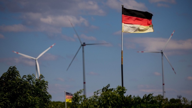 German national flags near wind turbines operated by Salzgitter AG, part of the Salzgitter Low CO2 Steelmaking (SALCOS) green steel project, at the company's mill in Salzgitter, Germany, on Tuesday, July 5, 2022. Salzgitter is looking to transform billowing foundries dating back decades into green steel production in a project to remain viable for years to come and a key test of German industry's ability to transition to cleaner technologies. Photographer: Krisztian Bocsi/Bloomberg