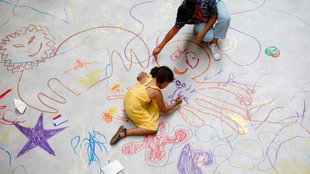 A child and a visitor draw on the floor of the Turbine Hall during a photocall for the "UNIQLO Tate Play: Mega Please Draw Freely" at Tate Modern art gallery, which opens on July 24, in London, U.K., on Friday, July 23, 2021. The project, UNIQLO Tate Play, by artist Ei Arakawa, is a part of the gallery's new art-inspired free programs for families. Unlike other European capitals, London is taking longer to reawaken from its 2020 slumber. Photographer: Hollie Adams/Bloomberg