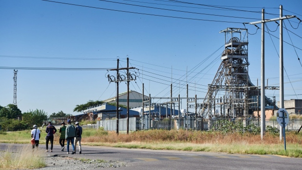 <p>Workers walk along the road outside an Impala Platinum Holdings mine.</p>