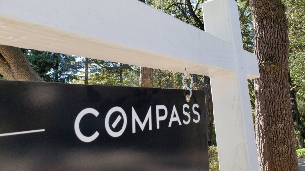 Close-up of a Compass Real Estate hanging sign panel in a wooded area, Lafayette, California. Source: Smith Collection/Gado/Getty Images