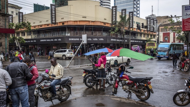 Motorcycle taxi drivers wait on the corner for passengers as Samsung Electronics Co. advertising hoardings cover a building beyond in downtown Nairobi, Kenya, on Thursday, April 23, 2020. Kenya's economic growth could slow to as low as 1% this year as effects of the coronavirus pandemic take a toll on businesses and revenue, according to the National Treasury Secretary Ukur Yatani. Photographer: Patrick Meinhardt/Bloomberg