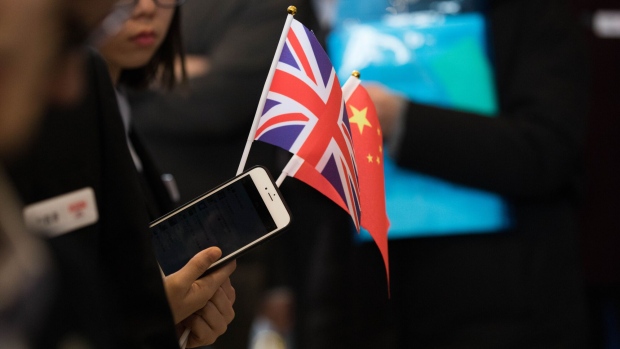 A visitor holding a Chinese flag and a Union flag, also known as a Union Jack, waits at a youth festival exhibition attended by Theresa May, U.K. prime minister, not pictured, at Wuhan university in Wuhan, China, on Wednesday, Jan. 31, 2018. May arrived in China seeking to balance her desire to build a powerful post-Brexit trade relationship with a clutch of political concerns. Photographer: Chris Ratcliffe/Bloomberg