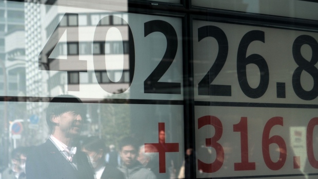 Pedestrians reflected in the windows of a securities firm in Tokyo. Photographer: Soichiro Koriyama/Bloomberg