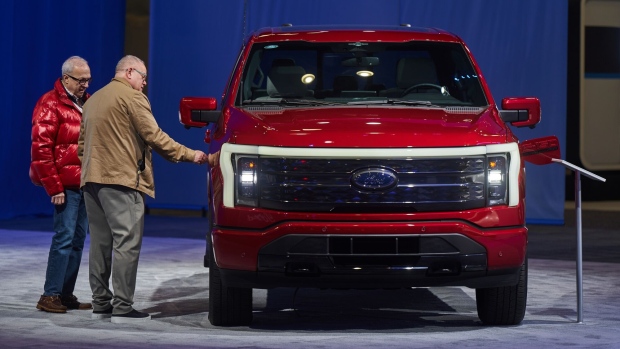 <p>Attendees examine a 2024 Ford F-150 Lightning Platinum electric pickup truck.</p>