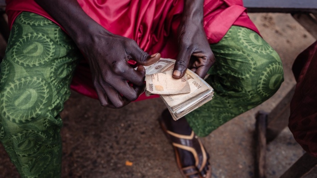 A street currency dealer holds Nigerian 1000 naira banknotes at a market in Lagos, Nigeria. Photographer: Benson Ibeabuchi/Bloomberg