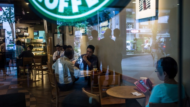 Customers sit inside a Starbucks Corp. cafe in Kuala Lumpur. Photographer: Sanjit Das/Bloomberg