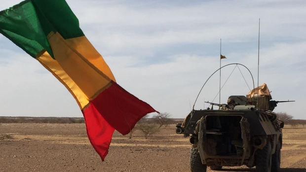 Soldiers patrol in a military vehicle next to a Malian national flag. Photographer: Daphne Benoit/AFP/Getty Images