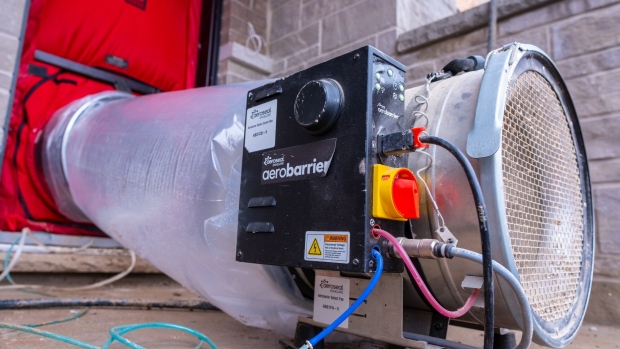 A centrifgal fan with tubing is attached to a blower door, where atomized sealant fog follows air currents through air leaks and seals them, at a home in Milton, Canada.  Photographer: Adetona Omokanye/Bloomberg