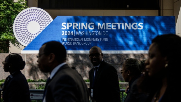 <p>Attendees walk past signage for the International Monetary Fund and World Bank spring meetings outside the IMF headquarters in Washington, DC on April 15.</p>