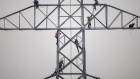 <p>Technicians work on an unconnected transmission tower.</p>