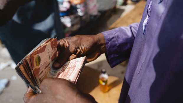 A trader counts Ghana cedi banknotes at Tudu market in Accra, Ghana, on Monday, March 11, 2024. Ghana is resisting calls by holders of the country's eurobonds to offer a sweetener for restructuring $13 billion of debt, risking a self-imposed deadline for a deal. Photographer: Ernest Ankomah/Bloomberg