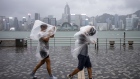 Pedestrians brace from the wind and rain on the waterfront in Tsim Sha Tsui district during a No. 8 storm signal raised for Super Typhoon Saola in Hong Kong, China, on Friday, Sept. 1, 2023. Hong Kong hunkered down on Friday as officials and residents prepared for the impact of Super Typhoon Saola, which is forecast to hit the city toward the end of the day. Photographer: Justin Chin/Bloomberg