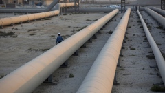 An employee walks along transport pipes leading to oil storage tanks at the Juaymah tank farm at Saudi Aramco's Ras Tanura oil refinery and oil terminal in Ras Tanura, Saudi Arabia, on Monday, Oct. 1, 2018. Saudi Aramco aims to become a global refiner and chemical maker, seeking to profit from parts of the oil industry where demand is growing the fastest while also underpinning the kingdom’s economic diversification. Photographer: Simon Dawson/Bloomberg