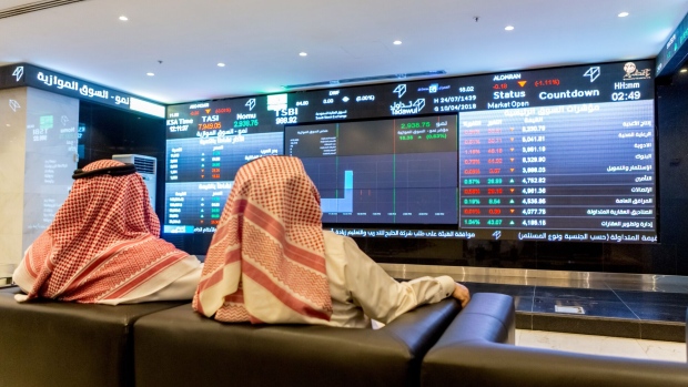 Visitors sit in a room displaying stock price information displayed on a digital screen inside the Saudi Stock Exchange, also known as the Tadawul, in Riyadh, Saudi Arabia, on Tuesday, April 10, 2018. Foreign investors bought more Saudi stocks in March than ever before in anticipation of the kingdom’s upgrade to emerging-market status. Photographer: Abdulrahman Abdullah/Bloomberg