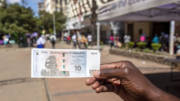 A bank customer displays a ten ZiG banknote in a street in Harare, Zimbabwe, on Tuesday, April 30, 2024. The southern African nation that’s had bouts of hyperinflation and triple-digit inflation introduced ZiG, short for Zimbabwe Gold on April 5. Photographer: Cynthia R Matonhodze/Bloomberg