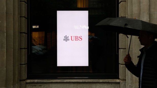 A digital display in the window of the UBS Group AG headquarters in Zurich, Switzerland on Tuesday, May 7, 2024. UBS Group AG returned to profit after two loss-making quarters, with both wealth management and the investment bank adding to sustained progress in the integration of Credit Suisse after its emergency rescue last year. Photographer: Stefan Wermuth/Bloomberg