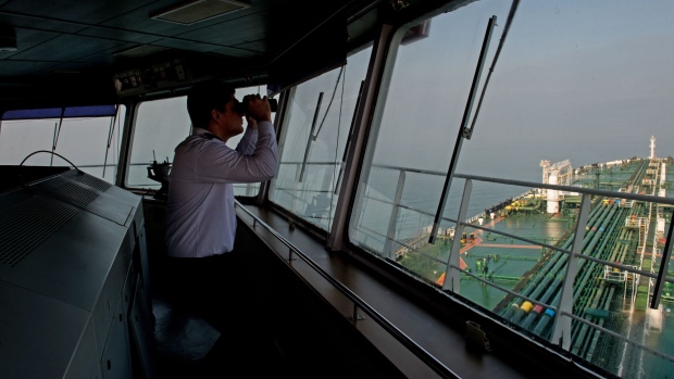 A crew member uses binoculars on the bridge of the oil tanker 'Devon' as it prepares to transfer crude oil from Kharg Island oil terminal to India, in the Persian Gulf, Iran, on Friday, March 23, 2018. Geopolitical risk is creeping back into the crude oil market. Photographer: Ali Mohammadi/Bloomberg