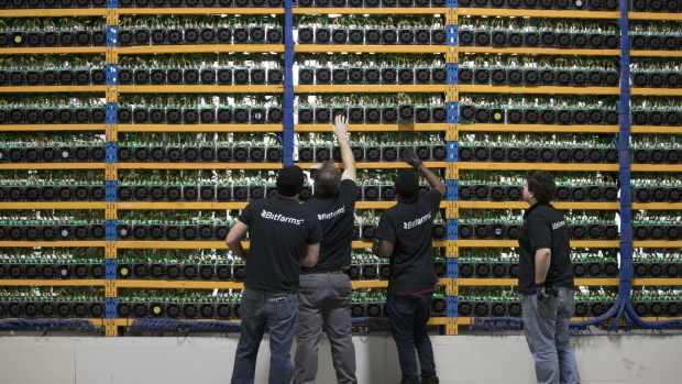 <p>Employees check mining machines at the Bitfarms cryptocurrency farming facility in Farnham, Quebec.</p>