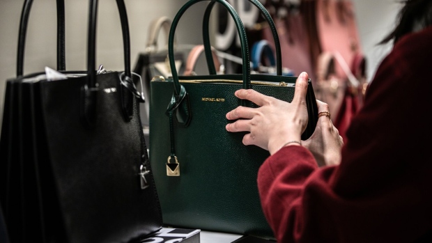 <p>A shopper looks at a Michael Kors handbag.</p>