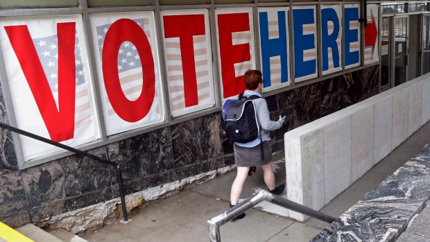 A woman passes a large sign as she arrives to vote early on Friday, Sept. 23, 2016, in Minneapolis. 