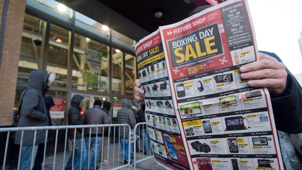 A man looks at a flyer offering discounts outside an electronics store on Boxing Day, in Montreal