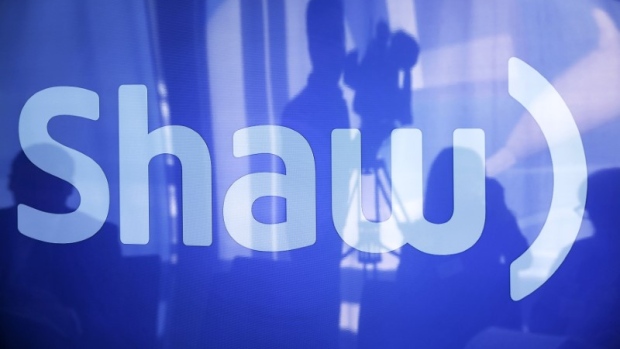 A television cameraman is reflected on a television screen displaying the Shaw logo