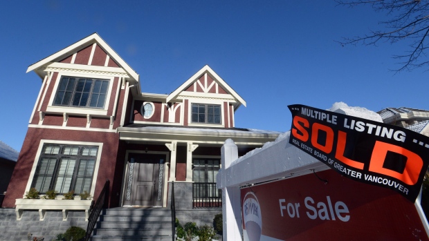 A real estate sold sign is shown outside a house in Vancouver