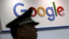 A security guard keeps watch as he walks past a logo of Google in Shanghai