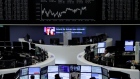 Traders work in front of the German share price index, DAX board, at the stock exchange in Frankfurt