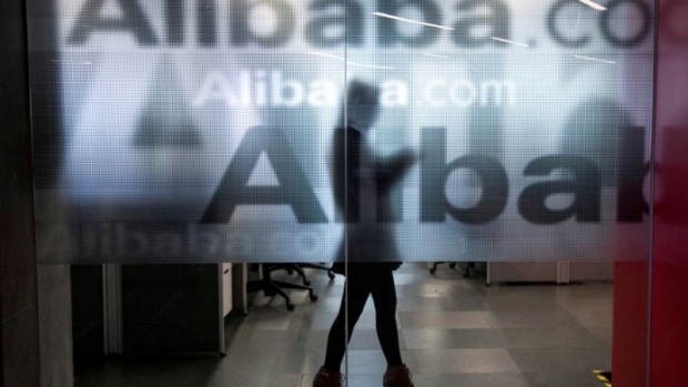 An employee is seen behind a glass wall with the logo of Alibaba at the company's headquarters