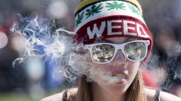 A woman exhales while smoking a joint during the annual 420 marijuana rally on Parliament Hill