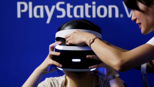 A hostess helps a woman to wear Sony's PlayStation VR headset at Tokyo Game Show 2016 in Chiba