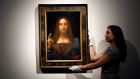 An employee poses with Leonardo da Vinci's 'Salvator Mundi'