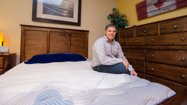 Mike Cleaver poses with a new waterbed at his mattress store in Barrie, Ont., Dec. 21, 2017