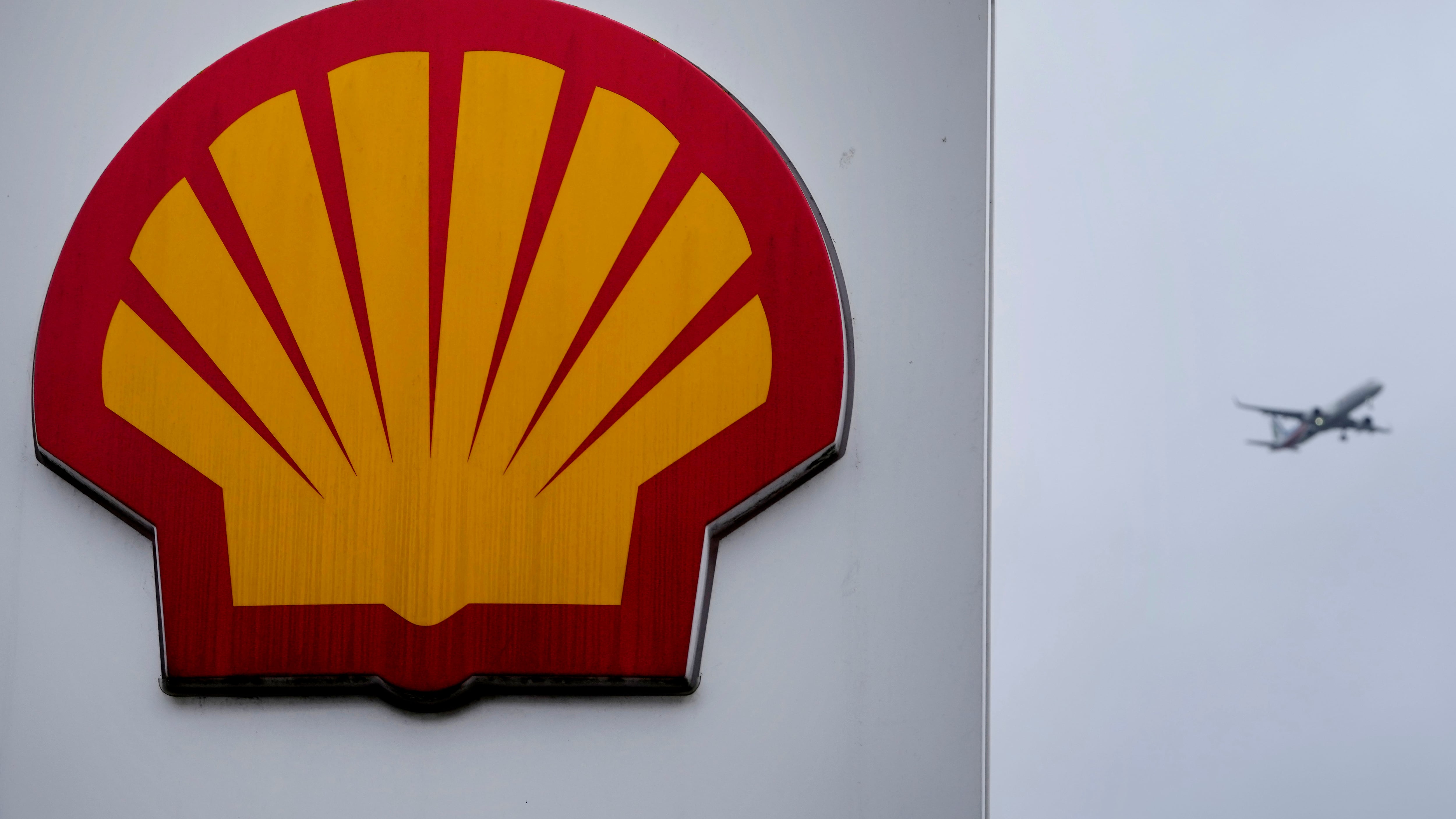 An aircraft passes a sign at a Shell petrol station in London on Feb. 2, 2023. (Kirsty Wigglesworth / AP Photo)