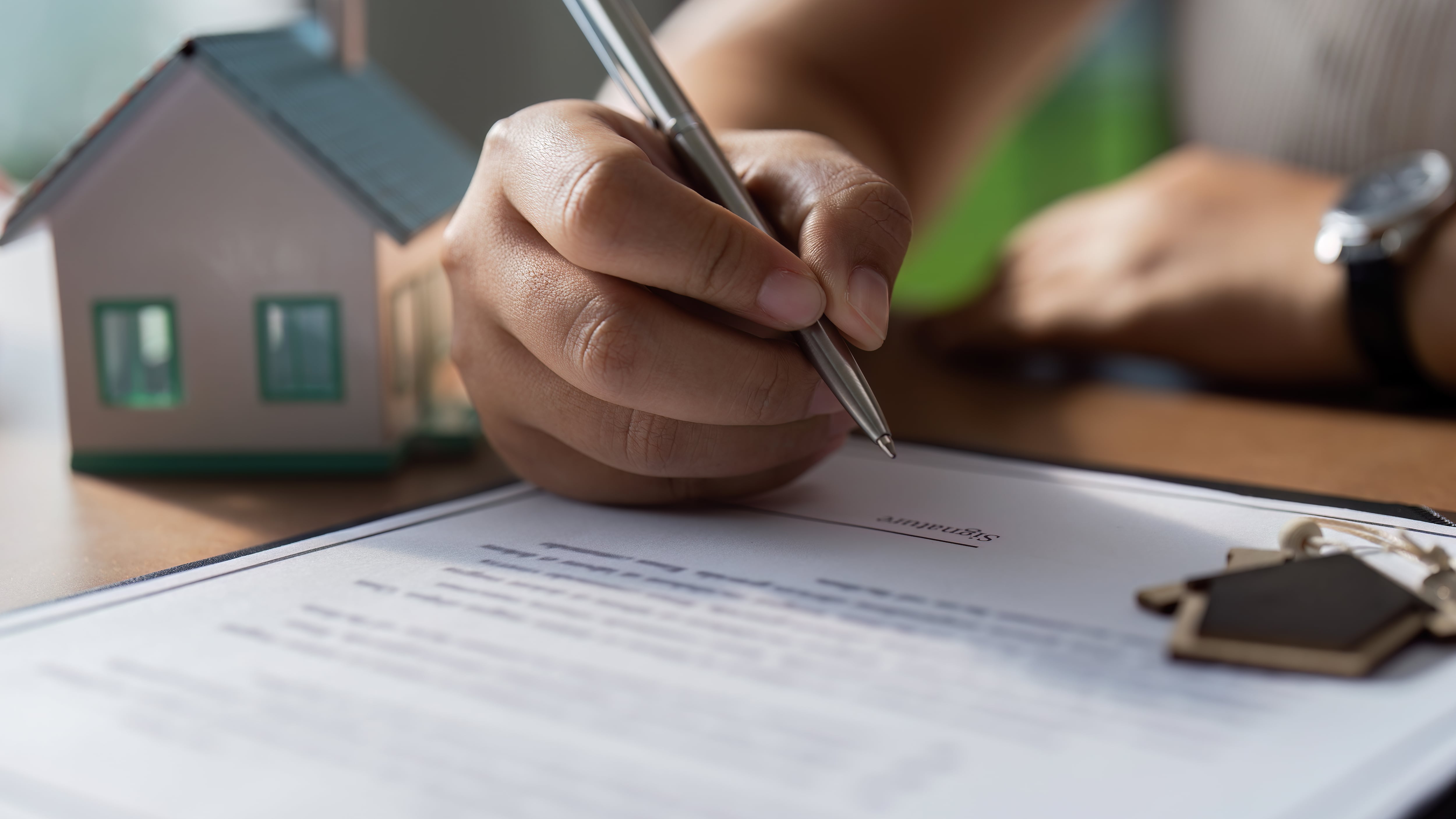 Une femme signe une offre d'achat pour une maison.